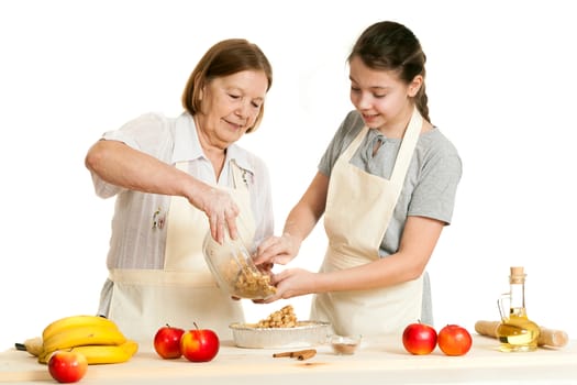 the grandmother and the granddaughter stack a stuffing in a form for pie