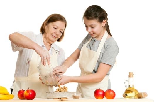 the grandmother and the granddaughter stack a stuffing in a form for pie
