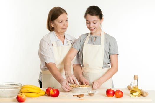 the grandmother and the granddaughter stack a stuffing in a form for pie