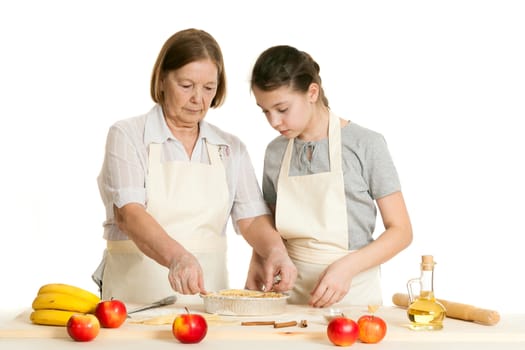 the grandmother and the granddaughter stack dough strips for ornament in a form for pie