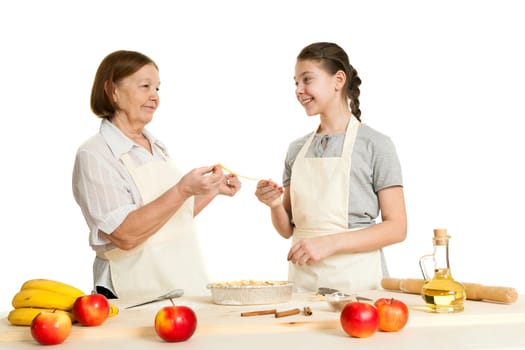 the grandmother and the granddaughter stack dough strips for ornament in a form for pie
