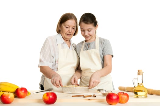 the grandmother and the granddaughter stack dough strips for ornament in a form for pie
