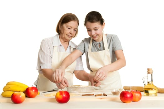 the grandmother and the granddaughter stack dough strips for ornament in a form for pie
