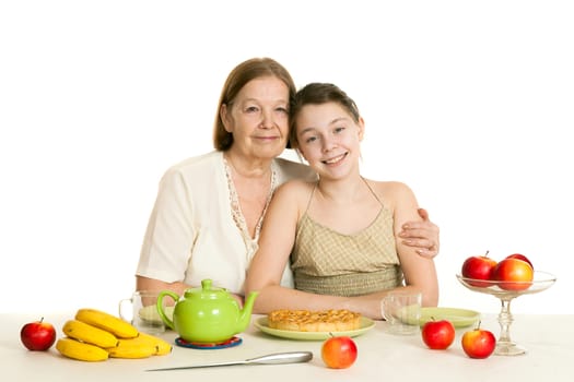 the grandmother and the granddaughter sit at a table with the made pie