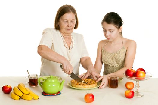 the grandmother treats the granddaughter with pie at a table