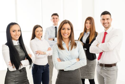 Smiling group of young business people standing with arms crossed and lookingat camera.