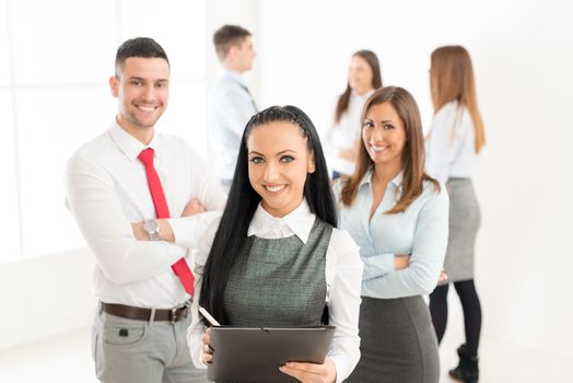 Successful young businesswoman standing proudly with her young business team and looking at the camera.