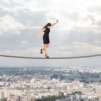 Businesslady walking on rope and looking down