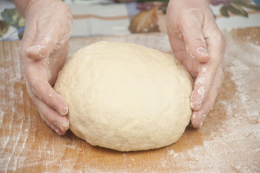 Hands baking dough with rolling pin on wooden table, depth of field