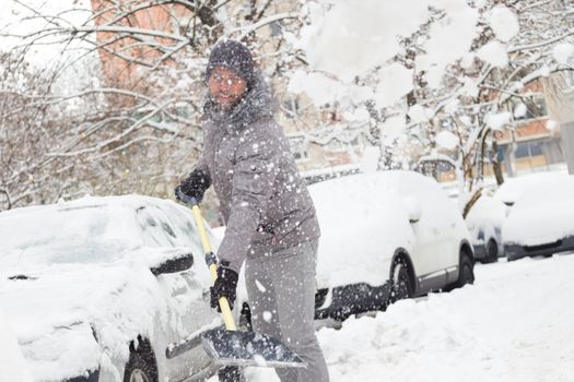 Man shoveling her parking lot after a winter snowstorm.