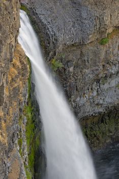 The canyon at the falls is 115 meters (377 feet) deep, exposing a large cross-section of the Columbia River Basalt Group. These falls and the canyon downstream are an important feature of the channeled scablands created by the great Missoula Floods that swept periodically across eastern Washington and across the Columbia River Plateau during the Pleistocene epoch. The ancestral Palouse river flowed through the currently dry Washtucna Coulee to the Columbia River. The Palouse Falls and surrounding canyons were created when the Missoula Floods overtopped the south valley wall of the ancestral Palouse River, diverting it to the current course to the Snake River by erosion of a new channel. The area is characterized by interconnected and hanging flood-created coulees, cataracts, plunge pools, kolk created potholes, rock benches, buttes and pinnacles typical of scablands. Palouse Falls State Park is located at the falls, protecting this part of the uniquely scenic area.