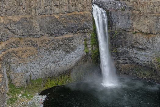 The canyon at the falls is 115 meters (377 feet) deep, exposing a large cross-section of the Columbia River Basalt Group. These falls and the canyon downstream are an important feature of the channeled scablands created by the great Missoula Floods that swept periodically across eastern Washington and across the Columbia River Plateau during the Pleistocene epoch. The ancestral Palouse river flowed through the currently dry Washtucna Coulee to the Columbia River. The Palouse Falls and surrounding canyons were created when the Missoula Floods overtopped the south valley wall of the ancestral Palouse River, diverting it to the current course to the Snake River by erosion of a new channel. The area is characterized by interconnected and hanging flood-created coulees, cataracts, plunge pools, kolk created potholes, rock benches, buttes and pinnacles typical of scablands. Palouse Falls State Park is located at the falls, protecting this part of the uniquely scenic area.
