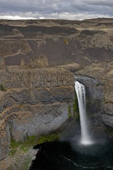 The canyon at the falls is 115 meters (377 feet) deep, exposing a large cross-section of the Columbia River Basalt Group. These falls and the canyon downstream are an important feature of the channeled scablands created by the great Missoula Floods that swept periodically across eastern Washington and across the Columbia River Plateau during the Pleistocene epoch. The ancestral Palouse river flowed through the currently dry Washtucna Coulee to the Columbia River. The Palouse Falls and surrounding canyons were created when the Missoula Floods overtopped the south valley wall of the ancestral Palouse River, diverting it to the current course to the Snake River by erosion of a new channel. The area is characterized by interconnected and hanging flood-created coulees, cataracts, plunge pools, kolk created potholes, rock benches, buttes and pinnacles typical of scablands. Palouse Falls State Park is located at the falls, protecting this part of the uniquely scenic area.
