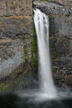 The canyon at the falls is 115 meters (377 feet) deep, exposing a large cross-section of the Columbia River Basalt Group. These falls and the canyon downstream are an important feature of the channeled scablands created by the great Missoula Floods that swept periodically across eastern Washington and across the Columbia River Plateau during the Pleistocene epoch. The ancestral Palouse river flowed through the currently dry Washtucna Coulee to the Columbia River. The Palouse Falls and surrounding canyons were created when the Missoula Floods overtopped the south valley wall of the ancestral Palouse River, diverting it to the current course to the Snake River by erosion of a new channel. The area is characterized by interconnected and hanging flood-created coulees, cataracts, plunge pools, kolk created potholes, rock benches, buttes and pinnacles typical of scablands. Palouse Falls State Park is located at the falls, protecting this part of the uniquely scenic area.