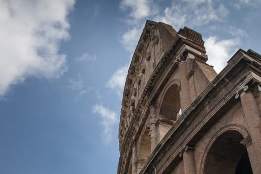 Although partially ruined because of damage caused by earthquakes and stone-robbers, the Colosseum is still an iconic symbol of Imperial Rome. Blue sky with clouds.