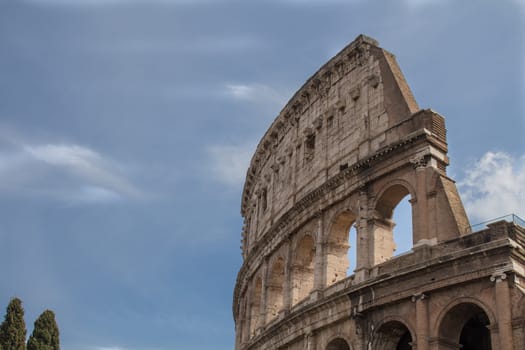 Although partially ruined because of damage caused by earthquakes and stone-robbers, the Colosseum is still an iconic symbol of Imperial Rome. Blue sky with clouds.