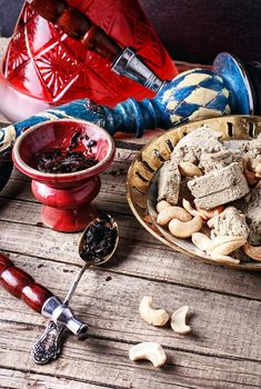 Composition with smoking hookah,tobacco and a plate of halva and cashews