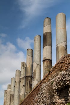 Old ruins of the marble columns close to Colosseum. Diagonal point of view. Cloudy sky.