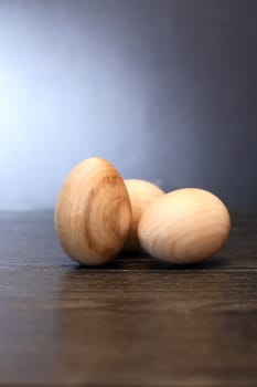 Three wooden eggs on table against gray background