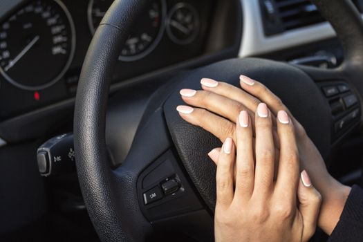 the girl with the manicure keeps hands on the steering wheel of the car