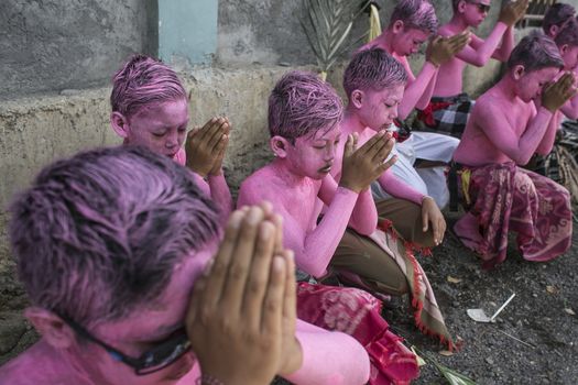 INDONESIA, Gianyar, Bali: Young members of the village community pray with their bodies painted, during the Grebeg ritual, on March 16, 2016, in Tegallalang village, Gianyar, Bali, Indonesia. During the biannual ritual, young members of the community para