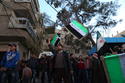 SYRIA, Saqba: A man holds a pre-Baath Syrian flag, that was adopted by the Syrian revolution during the uprising, on March 16, 2016 in Saqba, near Damascus, southern Syria, during a protest to mark the fifth anniversary of Syria's revolution. The conflict began with anti-regime protests in mid-March 2011 and spiralled into a bloody war after a harsh government crackdown on demonstrators. 