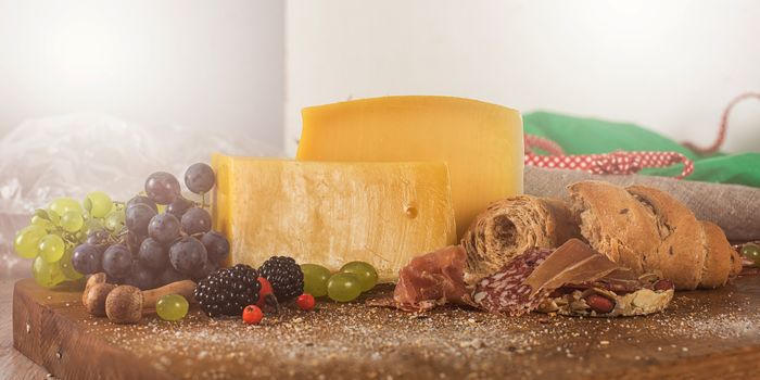 Fresh grapes, cheese bacon berries and salami on wooden table