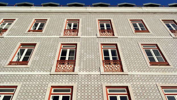 Detail of an old building with portuguese tiles and red and white windows, Lisbon, Portugal