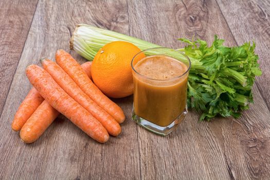 Blended dark orange smoothie with ingredients on wooden table