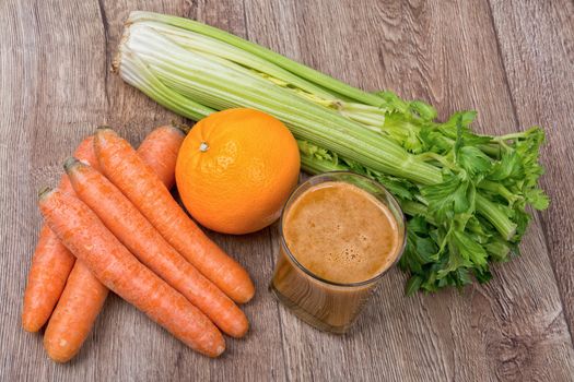 Blended dark orange smoothie with ingredients on wooden table