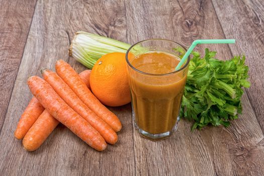 Blended dark orange smoothie with ingredients on wooden table
