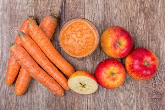 Blended light orange smoothie with ingredients on wooden table