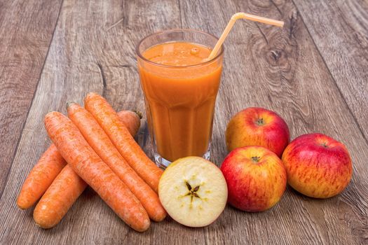 Blended light orange smoothie with ingredients on wooden table