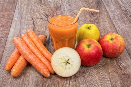 Blended light orange smoothie with ingredients on wooden table