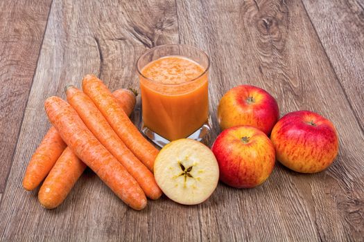 Blended light orange smoothie with ingredients on wooden table