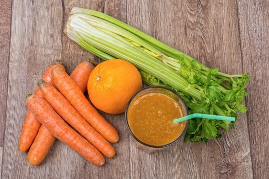 Blended dark orange smoothie with ingredients on wooden table