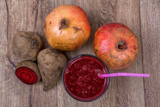 Blended dark red smoothie with ingredients on wooden table
