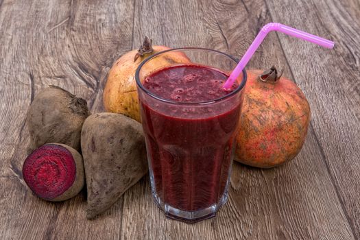 Blended dark red smoothie with ingredients on wooden table