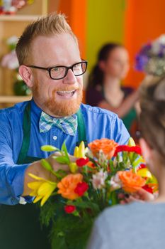 Helpful man selling arrangement in a busy flower shop
