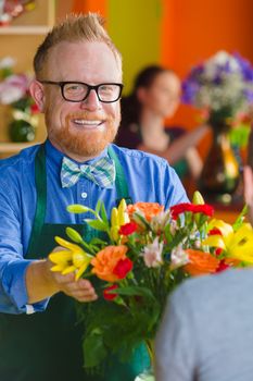 Smiling florist with arrangement in a busy flower shop