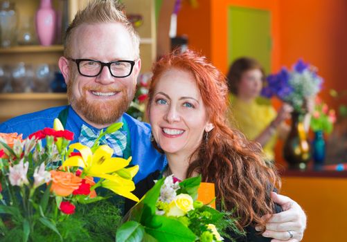 Attractive flower shop owners standing closely to each other in front of bouquet