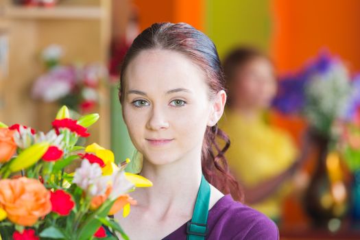 Pretty young woman holding bouquet in a busy flower shop