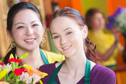 Two beautiful young female employees in a busy flower shop