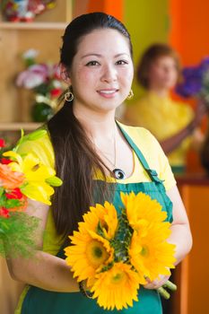 Pretty young woman with sunflower bouquet in a flower shop
