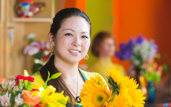 Cheerful young Asian woman with freckles in a flower shop