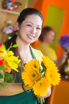 Attractive young woman in a flower shop holding bouquet of sunflowers