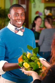 Satisfied customer in a busy flower shop being handed a bouquet
