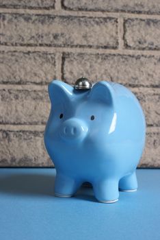 A blue pig bank rests up against a brick wall in this banking theme.
