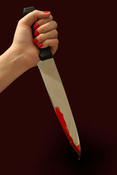 A woman grips a bloody knife in a killers pose.