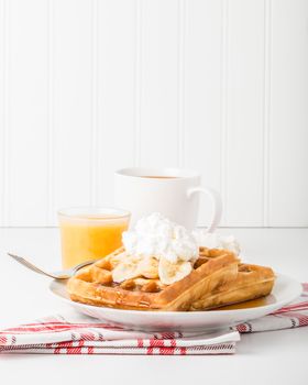 Delicious banana waffles with maple syrup and whipped cream.
